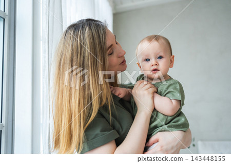 Happy family at home. Mother holding little toddler child daughter. Mom and baby girl relax playing having fun together at home. Mother hugging kissing baby with love care. Mom of breast feeding baby 143448155