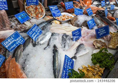 Various fresh seafood and raw fish arranged on ice with price tags at market stall 143448206