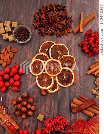 Recipe for delicious mulled wine featuring dried oranges, burnt sugar, cloves, nuts, cinnamon, star anise, rowan berries and rosehips, an abstract winter still life for the cold season, 143448397