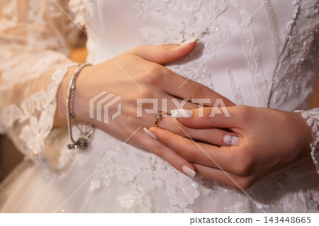 Closeup of bride's hands displaying diamond wedding rings on lace wedding dress with manicured nails Closeup of bride's hands displaying diamond wedding rings on lace wedding dress with manicured nails 143448665
