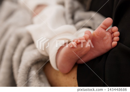 Infant Feet Resting on Adult Lap Under Soft Blanket Close-Up Infant Feet Resting on Adult Lap Under Soft Blanket Close-Up 143448686