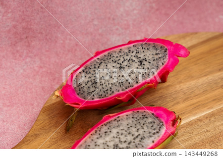 Vibrant dragon fruit halved on wooden board with textured background Vibrant dragon fruit halved on wooden board with textured background 143449268