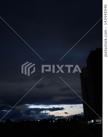 Dramatic dark stormy sky with low horizon and silhouetted building for moody background and evening landscape banner design 143449346