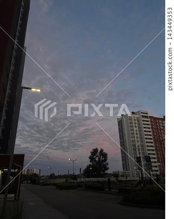 City skyline at dusk with tall apartment buildings and textured cloud sky for urban background and evening skyline banner City skyline at dusk with tall apartment buildings and textured cloud sky for urban background and evening skyline banner 143449353