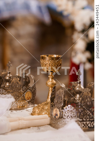Gold chalice with ornate crowns and white lace altar setting in Orthodox church for religious ceremony Gold chalice with ornate crowns and white lace altar setting in Orthodox church for religious ceremony 143449451