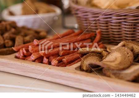 Sliced dried meat snacks arranged on a wooden serving platter with warm natural lighting Sliced dried meat snacks arranged on a wooden serving platter with warm natural lighting 143449462