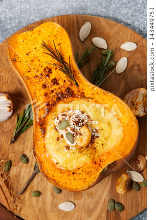 Delicious roasted butternut squash with creamy filling and toppings in a cozy kitchen setting 143449751