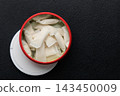 Snus pouches displayed in a round container on a dark surface showing several nicotine pads ready for use in a casual setting 143450009