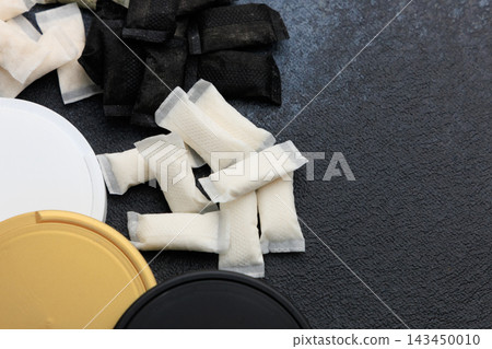 Snus pouches and nicotine pads arranged on a surface with different colored containers for storage and usage Snus pouches and nicotine pads arranged on a surface with different colored containers for storage and usage 143450010