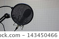 A round cloth pop filter in front of a microphone for reading text in a studio  143450466