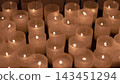 A multitude of lit votive candles glowing in the darkness of a traditional church 143451294