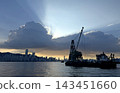 Silhouette of a construction barge on the water against a dramatic sunset Hong Kong city skyline view 143451660
