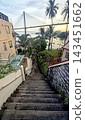 Steep concrete staircase leading down to a coastal view with a large cable-stayed suspension bridge 143451662