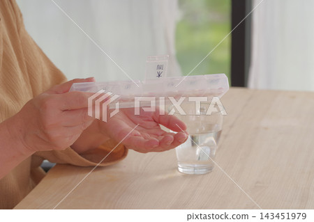 一位女士從藥盒裡取出藥物。 143451979