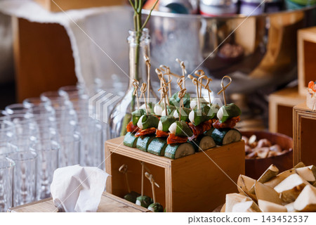 Appetizing vegetable skewers with green zucchini slices bacon and mozzarella arranged in rustic wooden box at event buffet Appetizing vegetable skewers with green zucchini slices bacon and mozzarella arranged in rustic wooden box at event buffet 143452537