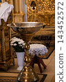 Large silver baptismal font with brass stand inside cathedral church interior near altar 143452572