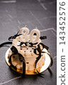 White frosting thirty birthday cake with black ribbons and candles on gold plate against dark grey slate background surface 143452576