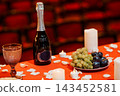 Champagne bottle with fruit platter and candles on red table in dark theater seats 143452581