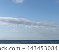 一縷雲朵飄過藍天，一艘船漂浮在平靜的地平線上。 143453084