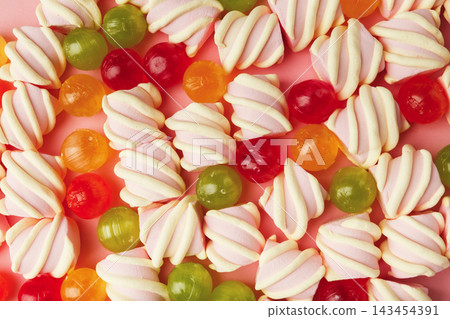 Closeup of heap of marshmallows and colourful sweets on pink background, flat lay. Confectionery store advertisement and sweet life concept. 143454391