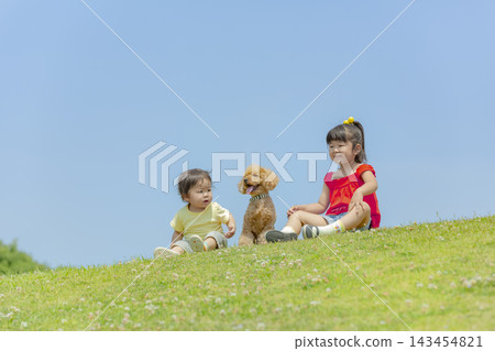 一對姐弟在公園裡和他們的寵物玩耍 一對姐弟在公園裡和他們的寵物玩耍 143454821