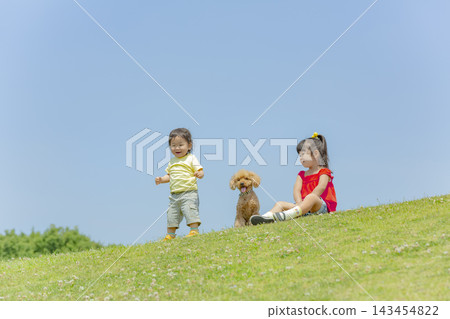 一對姐弟在公園裡和他們的寵物玩耍 一對姐弟在公園裡和他們的寵物玩耍 143454822