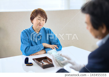 A specialist buyer who appraises precious metals and a senior woman A specialist buyer who appraises precious metals and a senior woman 143455333