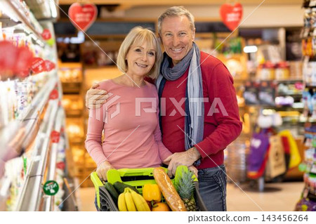Smiling Elderly Caucasian Couple Shopping Together In Supermarket, Holding Basket Filled With Fresh Fruits And Vegetables, Enjoying Quality Time While Making Healthy Choices At Store, Lifestyle Smiling Elderly Caucasian Couple Shopping Together In Supermarket, Holding Basket Filled With Fresh Fruits And Vegetables, Enjoying Quality Time While Making Healthy Choices At Store, Lifestyle 143456264
