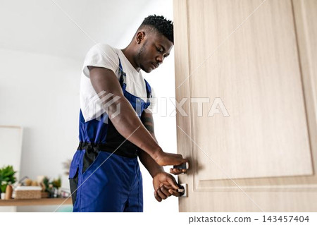 Focused African American Male Carpenter Working On Door Installation In Modern Home Setting, Engaged In Craftsmanship And Repair Activity, Showcasing Home Renovation Concept. 143457404
