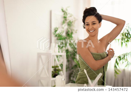 Happy Young Woman Smiling While Shaving Underarm With Razor In Bathroom. Taking Care Of Skin And Personal Grooming Routine, Promoting Self-care And Wellness In A Domestic Setting. 143457472