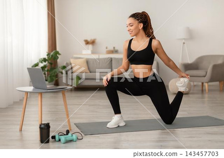 Happy Young Black Woman Stretching And Recovering After Home Workout Session, Performing Exercises On Yoga Mat In Modern Living Room. Weight Loss Concept. Happy Young Black Woman Stretching And Recovering After Home Workout Session, Performing Exercises On Yoga Mat In Modern Living Room. Weight Loss Concept. 143457703