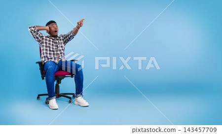 Excited Young Black Male With Facial Expression Showing Surprise While Sitting On Chair In Modern Office Setting, Engaging With Content Or Conversation, Weight Loss Concept. Excited Young Black Male With Facial Expression Showing Surprise While Sitting On Chair In Modern Office Setting, Engaging With Content Or Conversation, Weight Loss Concept. 143457709