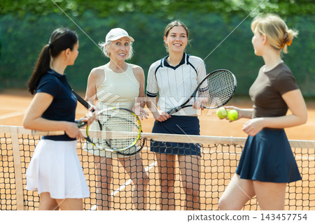 Group of women chatting on tennis court Group of women chatting on tennis court 143457754