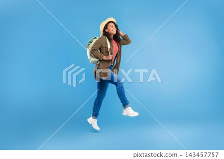 Smiling Black Woman With Backpack Hiking, Enjoying Adventure Outdoors, Walking In Nature, Energetic And Happy, Expressing Joy And Enthusiasm, Against Blue Background. Outdoor Adventure Concept. Smiling Black Woman With Backpack Hiking, Enjoying Adventure Outdoors, Walking In Nature, Energetic And Happy, Expressing Joy And Enthusiasm, Against Blue Background. Outdoor Adventure Concept. 143457757