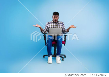 Worried Black Male Individual In His 20s Sitting At Office Chair, Using Laptop To Seek Information And Solutions, Showing Confusion About His Weight Loss Journey, Focused On Digital Resources. Worried Black Male Individual In His 20s Sitting At Office Chair, Using Laptop To Seek Information And Solutions, Showing Confusion About His Weight Loss Journey, Focused On Digital Resources. 143457807