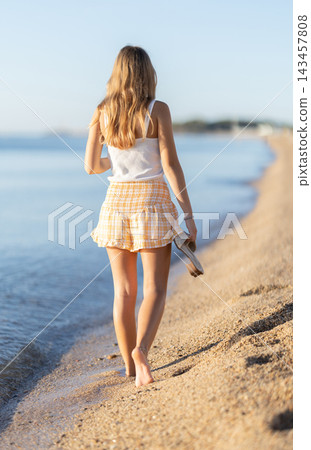 Girl is walking barefoot along sandy shore Girl is walking barefoot along sandy shore 143457808