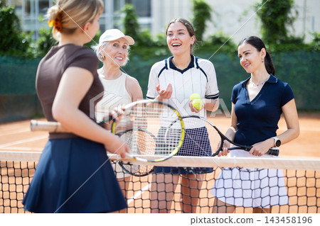 Group of women chatting on tennis court Group of women chatting on tennis court 143458196
