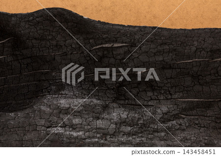 A piece of wood shows signs of damage from fire. The surface is blackened and shows cracks. The backdrop is a simple brown color. This detail emphasizes the effect of heat and fire on wood. A piece of wood shows signs of damage from fire. The surface is blackened and shows cracks. The backdrop is a simple brown color. This detail emphasizes the effect of heat and fire on wood. 143458451