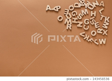 Scattered wooden letters lay on a brown surface. The letters are randomly placed, creating a simple scene. This setup is ideal for educational activities and crafting ideas. Scattered wooden letters lay on a brown surface. The letters are randomly placed, creating a simple scene. This setup is ideal for educational activities and crafting ideas. 143458536