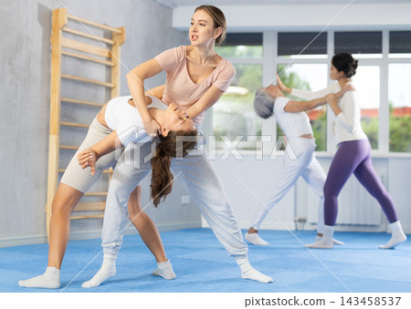 Woman and girl in gym perform basic elements of krav maga self-defense system. 143458537