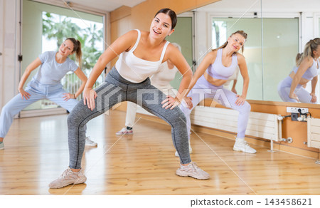 Women in casual clothes studying modern dance element in classroom Women in casual clothes studying modern dance element in classroom 143458621