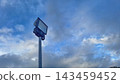 A tall floodlight pole stands against a blue sky filled with scattered clouds 143459452