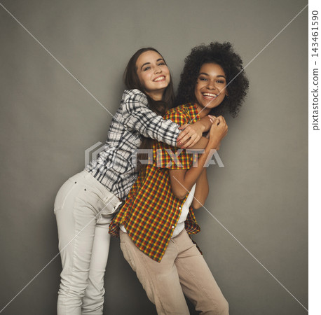 Two friends stand close together, laughing and enjoying their time. They pose playfully, creating a happy scene. The background is simple, allowing their friendship to stand out. Two friends stand close together, laughing and enjoying their time. They pose playfully, creating a happy scene. The background is simple, allowing their friendship to stand out. 143461590