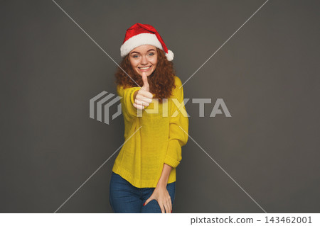 A person shows excitement and joy with a thumbs up gesture while wearing a yellow sweater and a Christmas hat. This collage captures festive spirit during the holiday season. 143462001