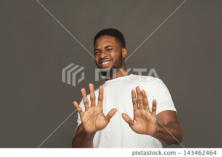 A man stands in a studio with a gray background. He has a playful expression while holding his hands up in front of him. His gesture suggests he is either joking or expressing surprise. A man stands in a studio with a gray background. He has a playful expression while holding his hands up in front of him. His gesture suggests he is either joking or expressing surprise. 143462464
