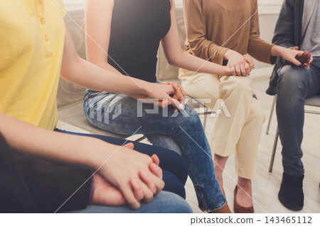 People sit in a circle, holding hands for support. The setting features soft lighting and simple chairs. Each person shows a sense of unity and connection as they engage in discussion. People sit in a circle, holding hands for support. The setting features soft lighting and simple chairs. Each person shows a sense of unity and connection as they engage in discussion. 143465112