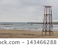A coastline with rough waves crashing against the shore and an old watchtower 143466288