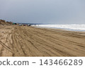 A coastal landscape featuring wide sandy beaches and rough waves. 143466289