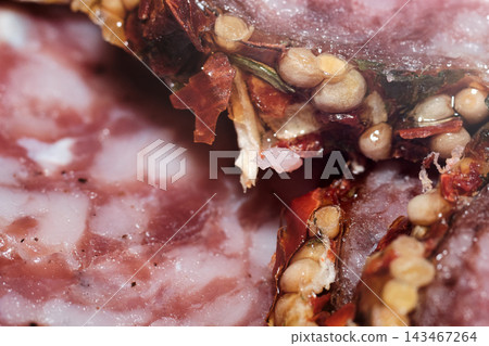 Extreme close-up shot of cured salami slice showing embedded whole mustard seeds and spices Extreme close-up shot of cured salami slice showing embedded whole mustard seeds and spices 143467264