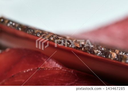 Macro close-up shot of thin sliced cured meat showing texture and seasoning Macro close-up shot of thin sliced cured meat showing texture and seasoning 143467285